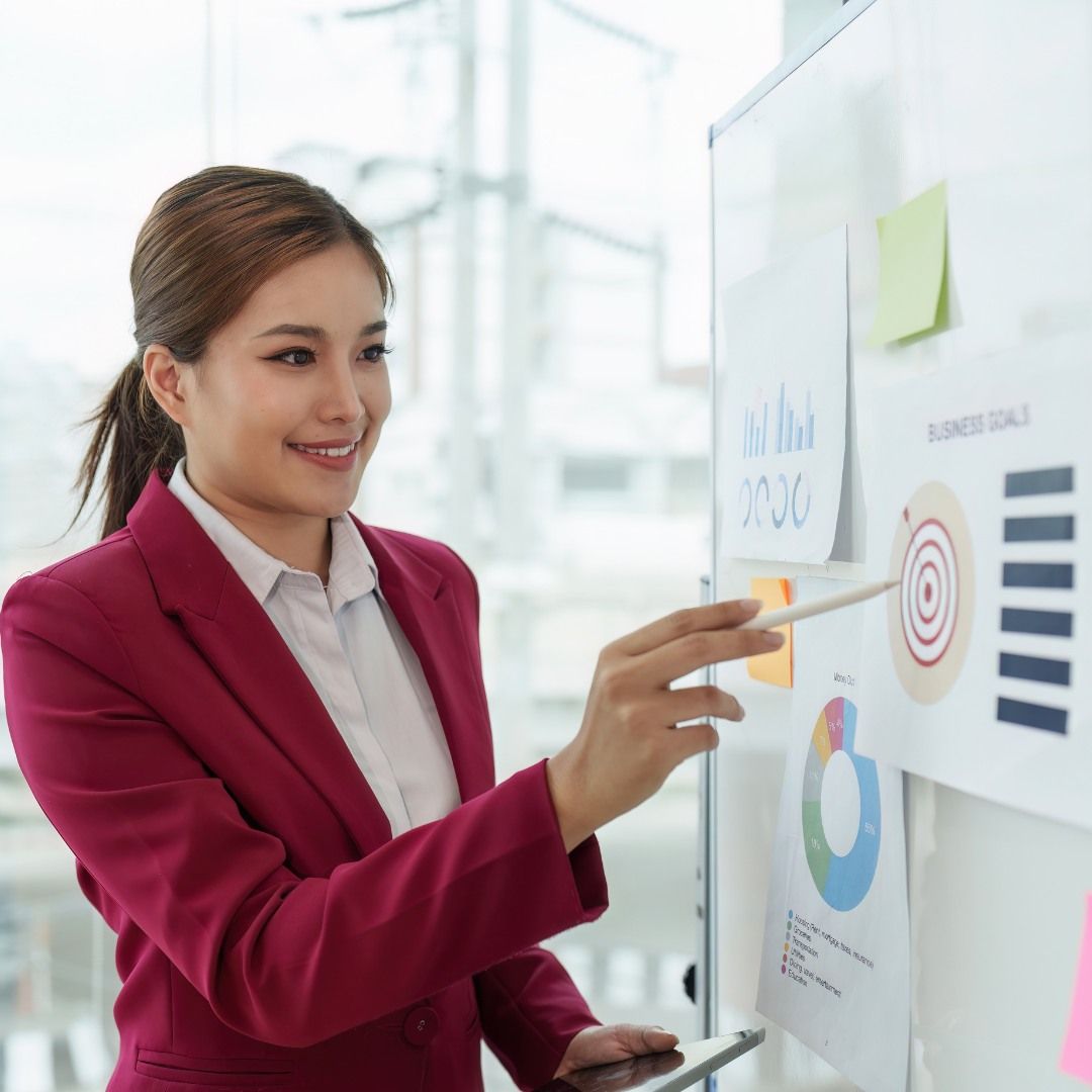 A Woman Smiles While Pointing At A Chart — Michelle Crutcher Business Coaching & Consulting in The Entrance North, NSW