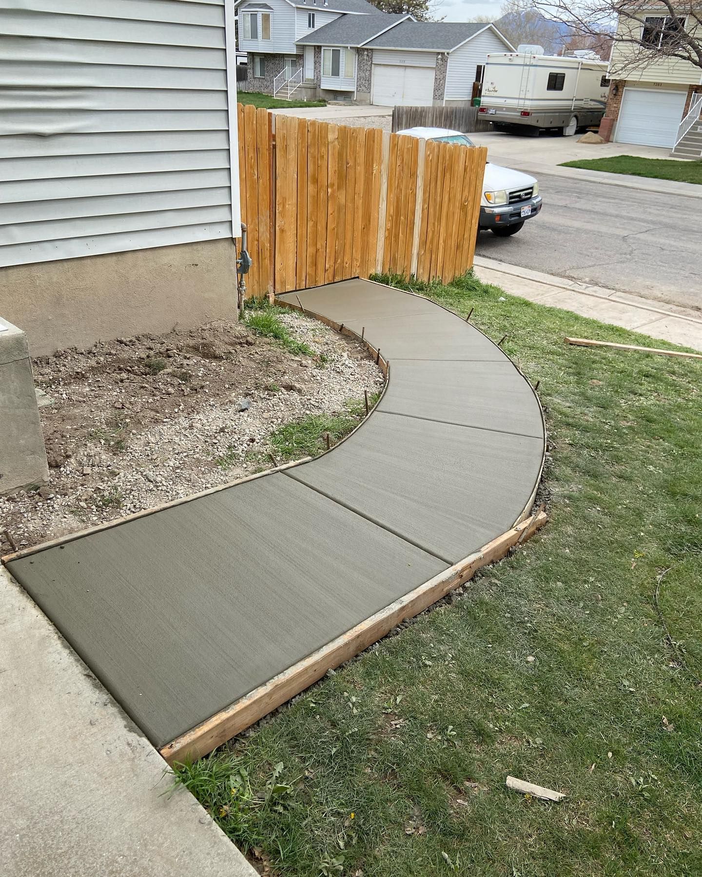 A concrete sidewalk is being built next to a wooden fence.