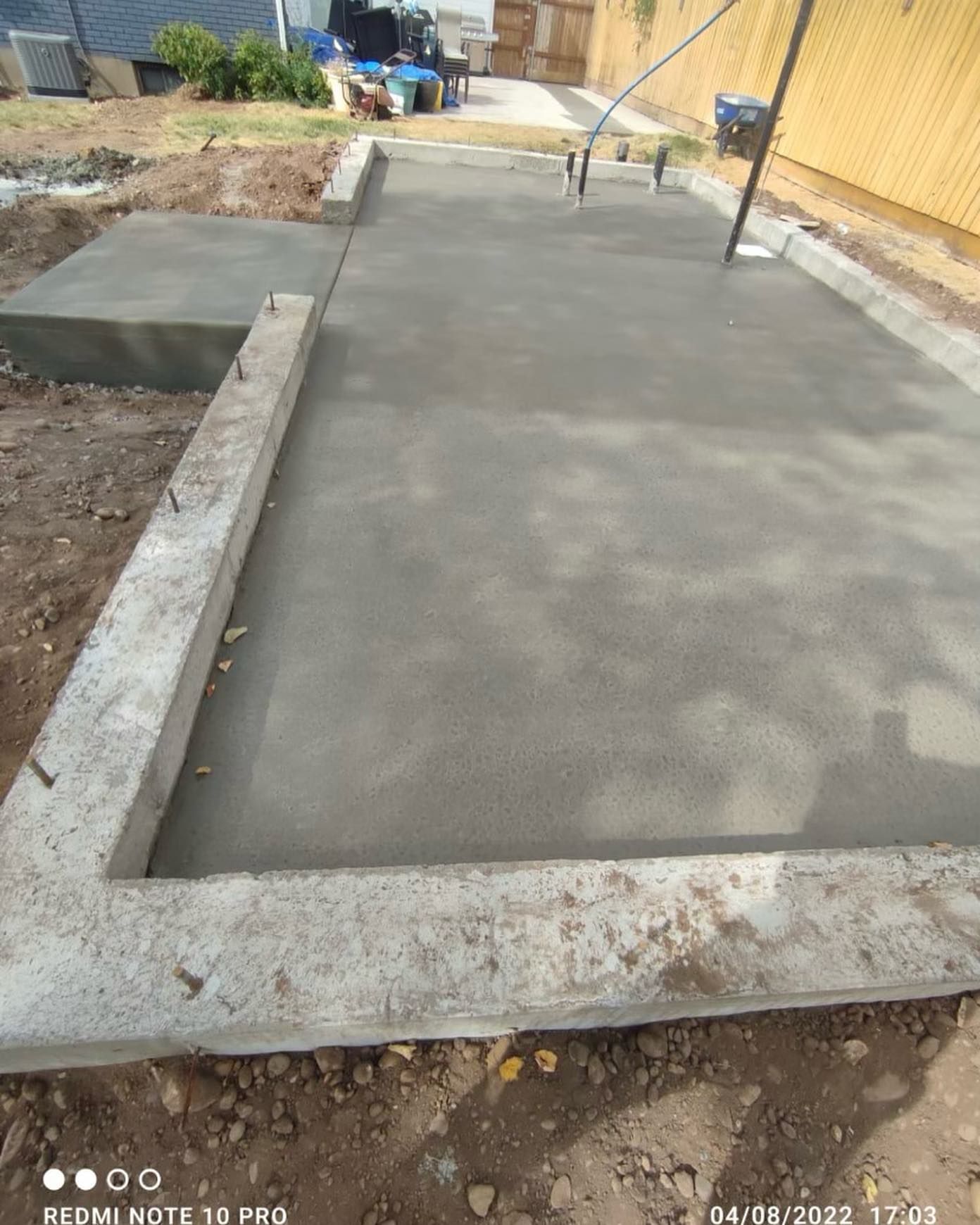 A concrete foundation is being built in a backyard.