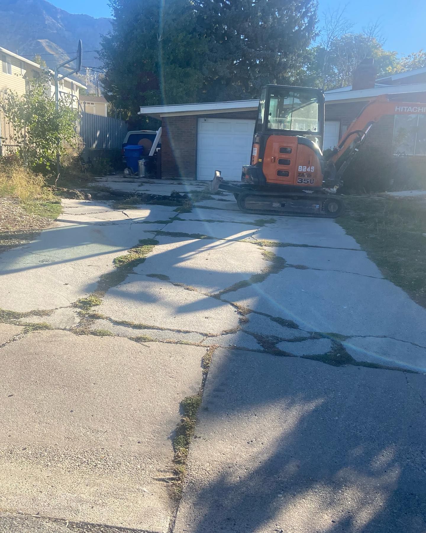A small excavator is parked on the sidewalk in front of a house.