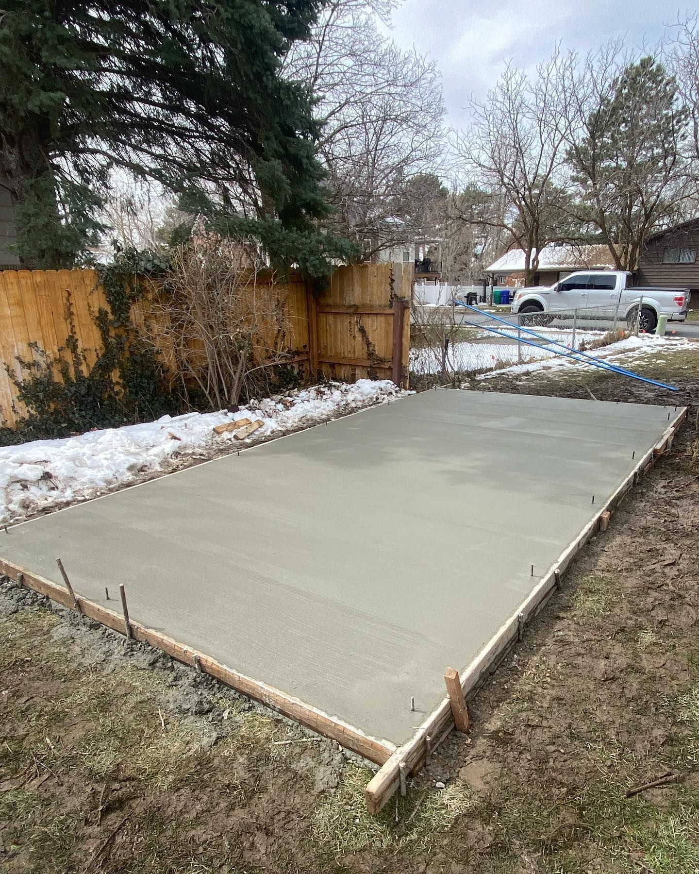 A concrete slab is being built in the backyard of a house.