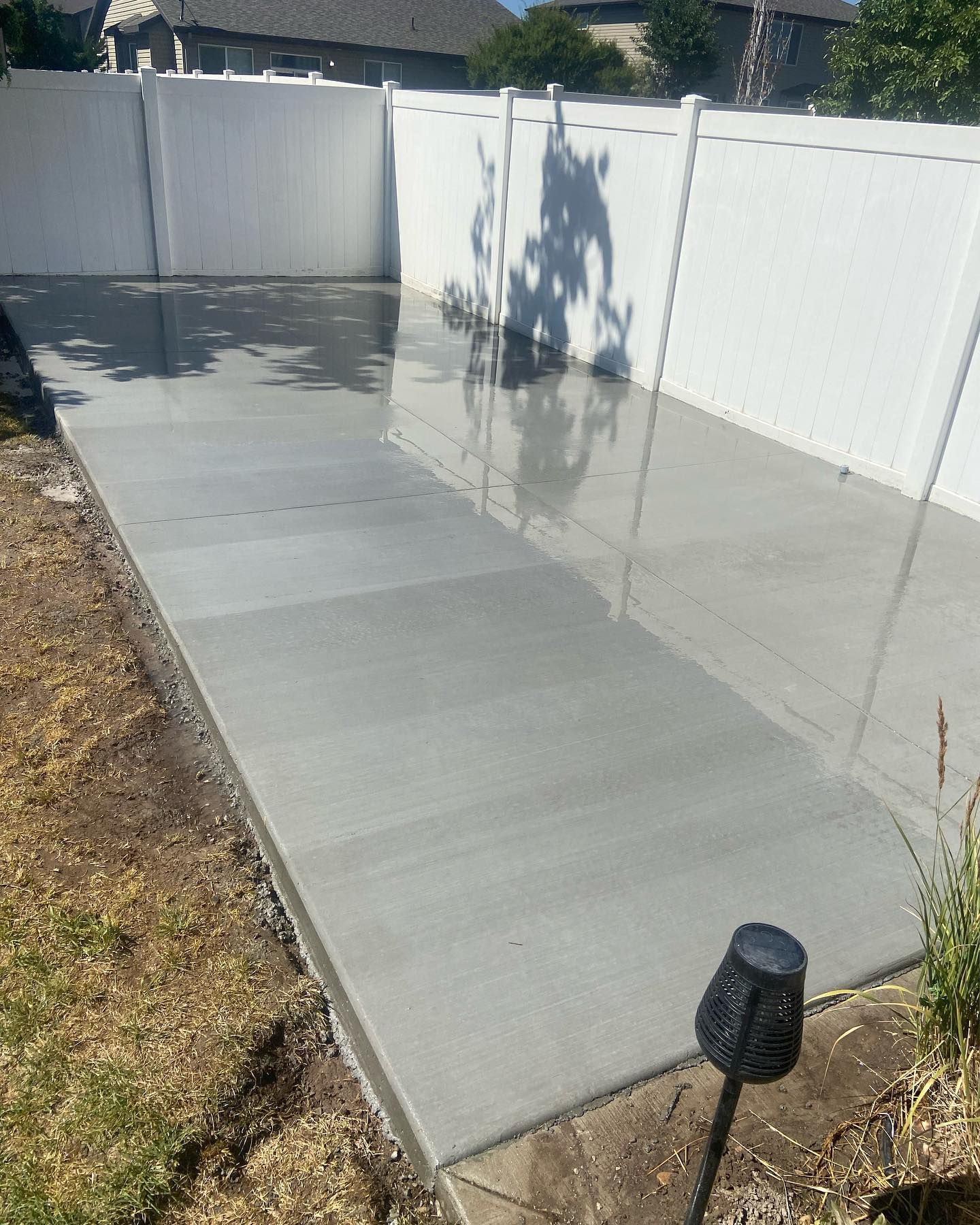 A concrete walkway with a white fence in the background.