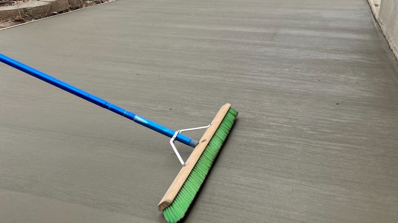 A broom is sitting on top of a concrete floor.