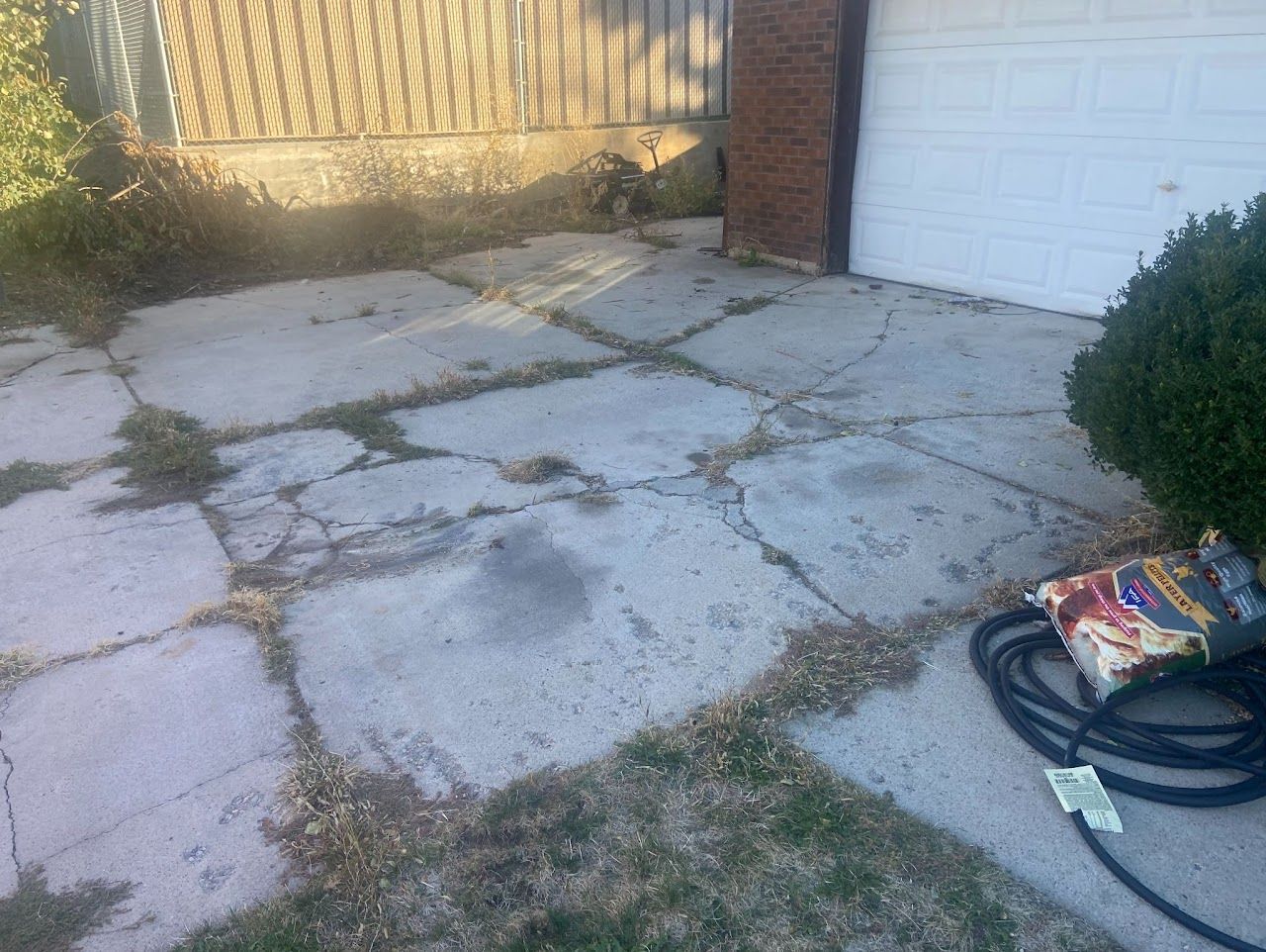 A hose is sitting on the sidewalk in front of a garage.