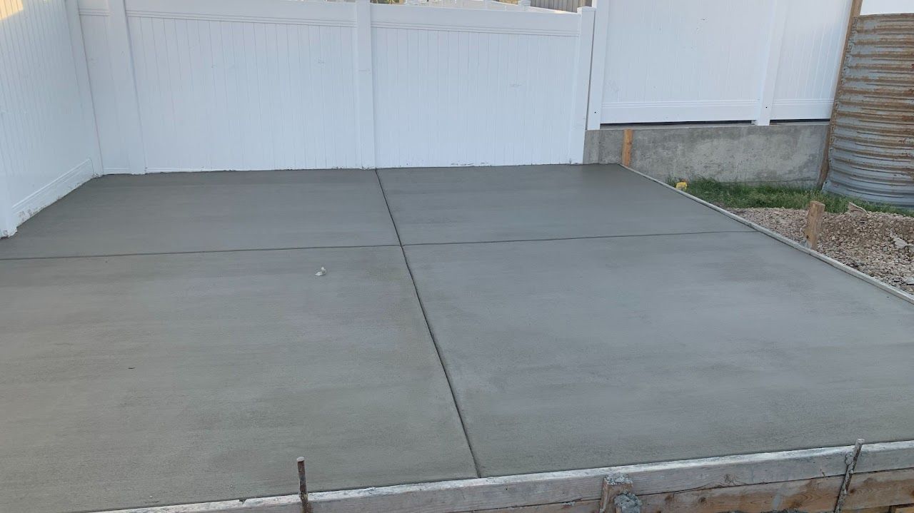 A concrete driveway is being built in front of a garage door.