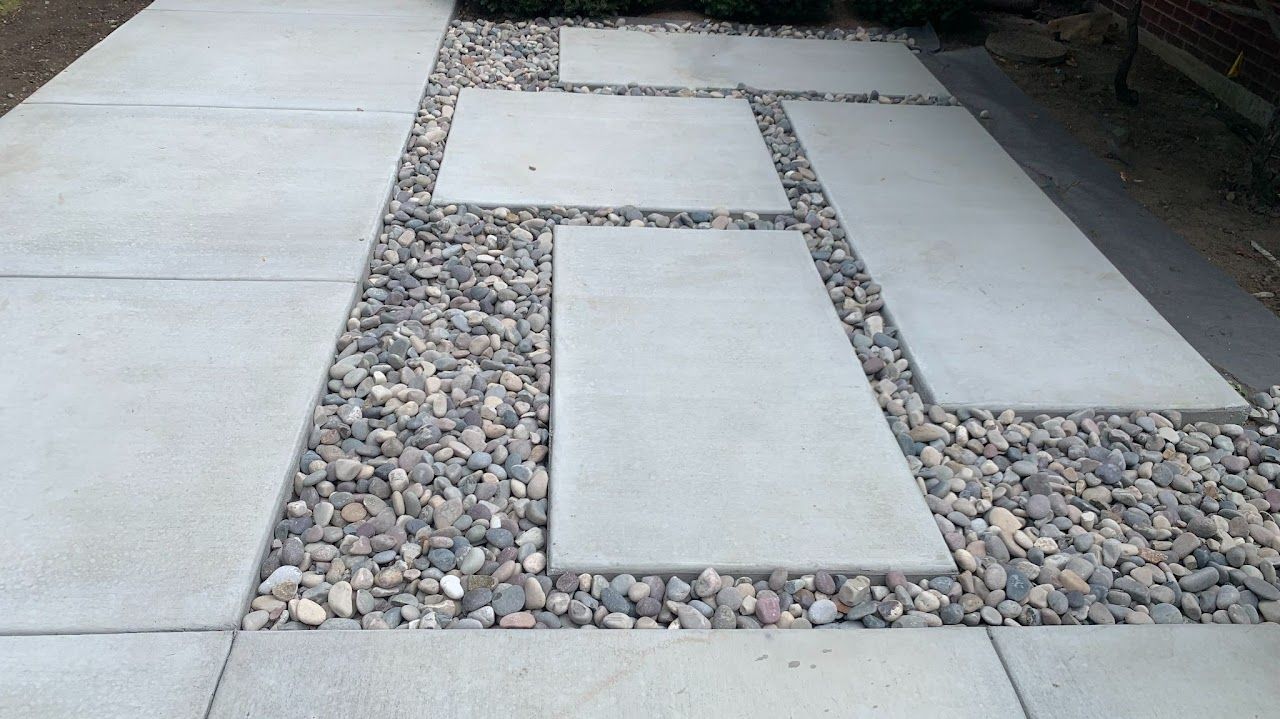 A concrete walkway with rocks on the side of it