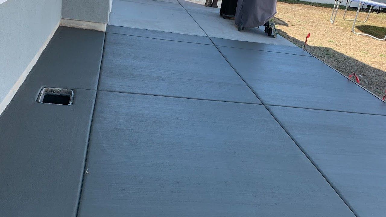 A person is walking down a concrete sidewalk next to a building.