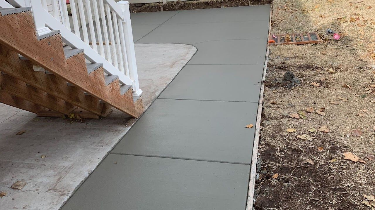 A concrete walkway next to a staircase with a white railing.
