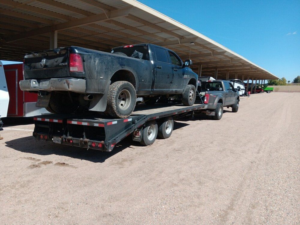 A truck is being towed on a trailer in a parking lot