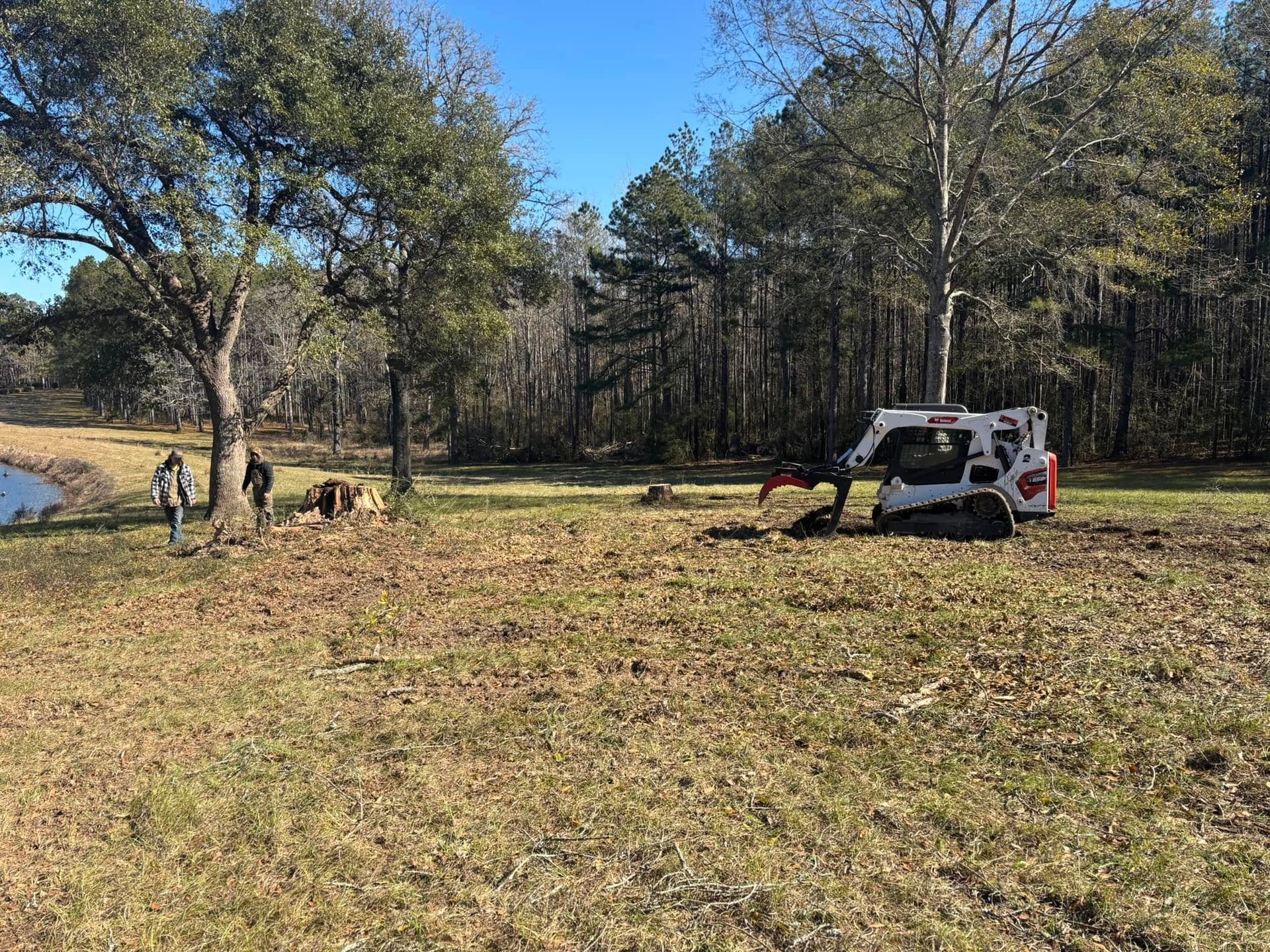 A bulldozer is sitting in the middle of a field next to a lake.
