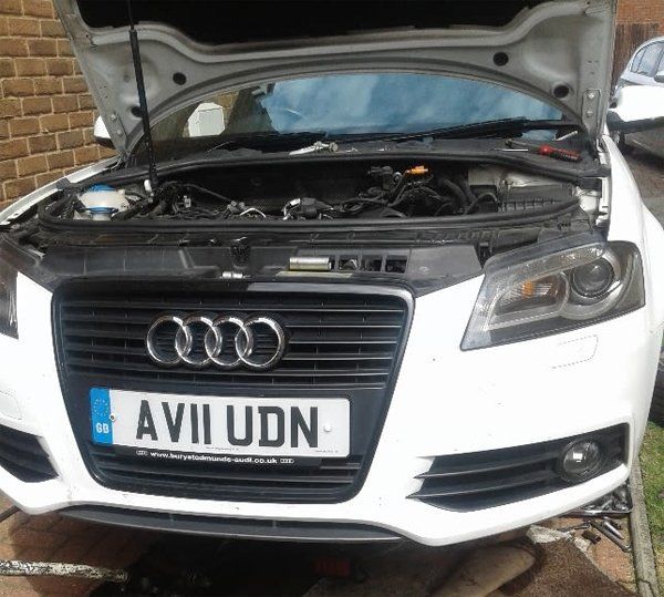 Picture of an Audi with its bonnet up while it is being fixed