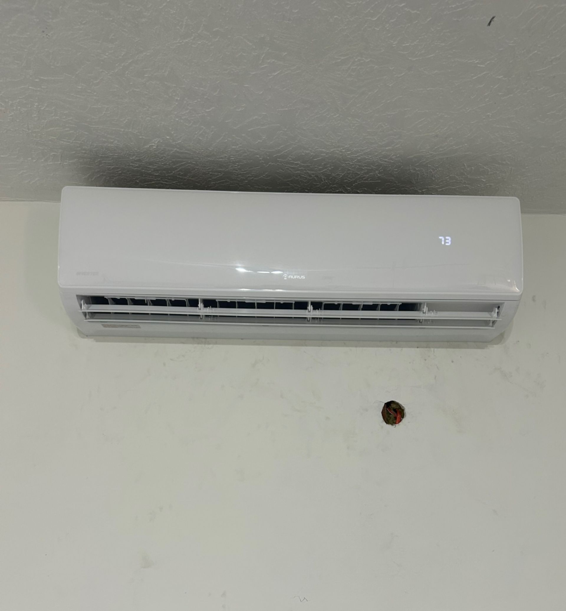 White air conditioner mounted on a white wall.