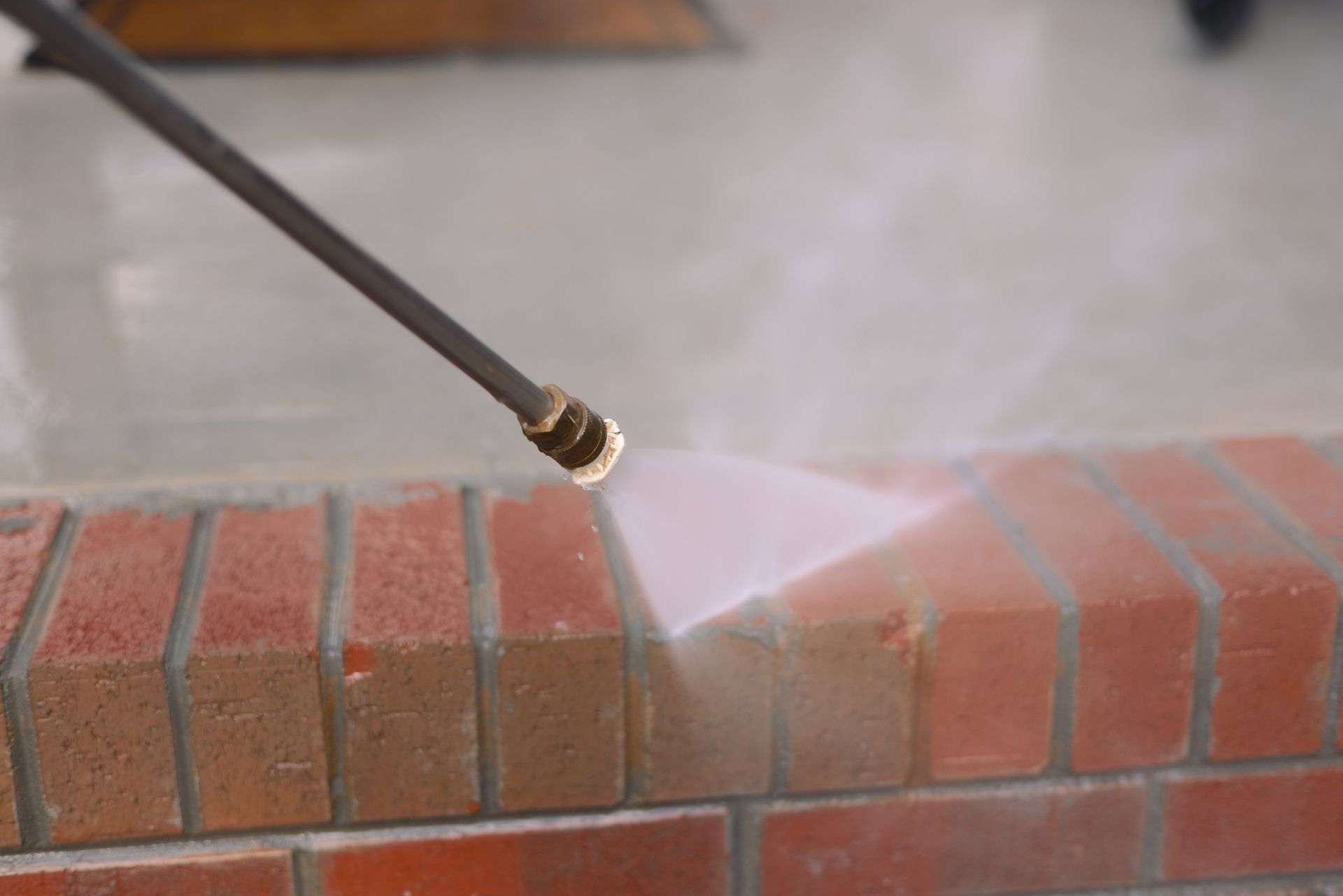 Pressure washing a brick ledge with a spray nozzle