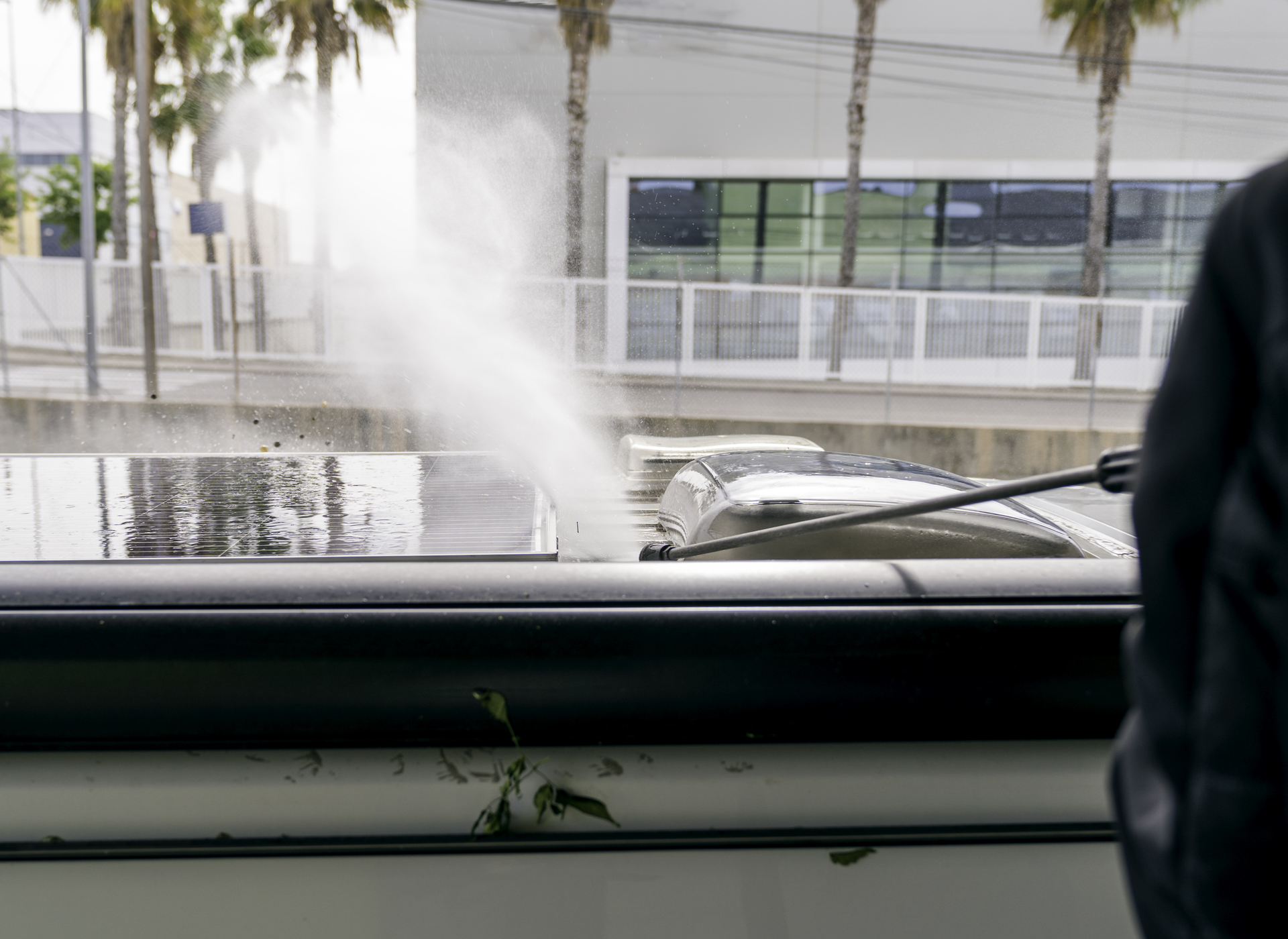 Car crashed into a fountain outside a modern building, spraying water over the street.
