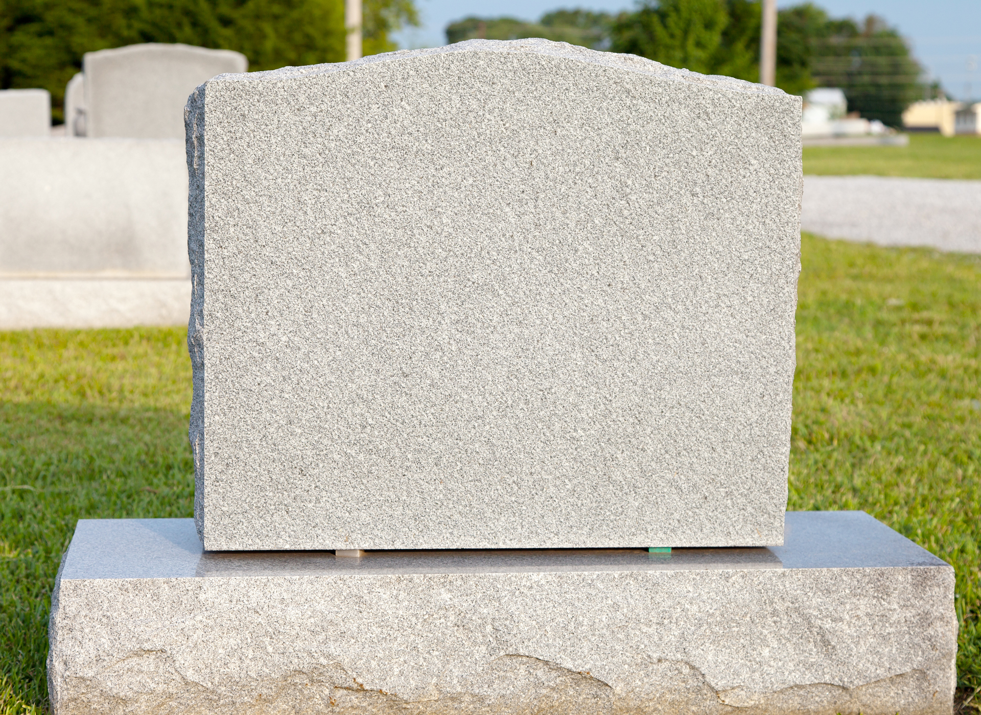 Plain gray gravestone in a cemetery on a sunny day