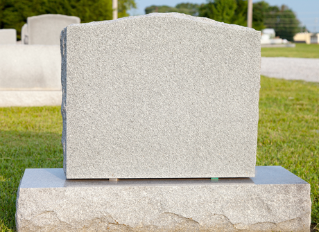 Plain gray gravestone in a cemetery on a sunny day