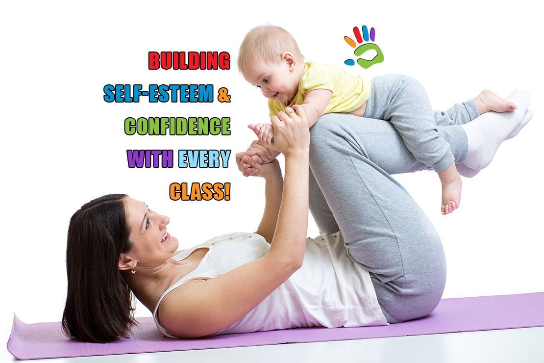 A woman is laying on a yoga mat holding a baby