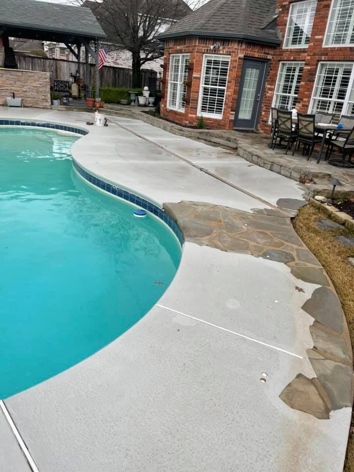 Curved concrete pool deck beside a turquoise pool and brick patio building on an overcast day