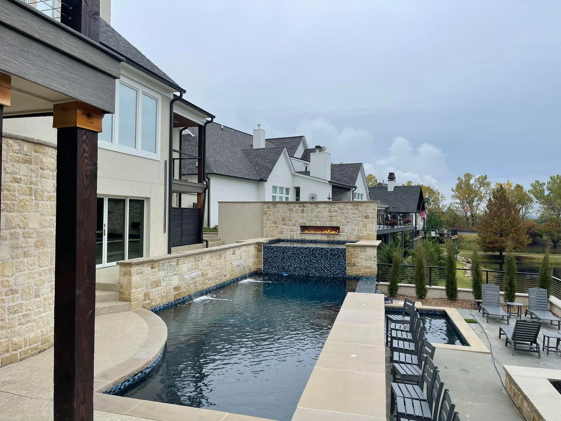 Modern backyard pool with stone coping beside a row of townhouses and outdoor seating