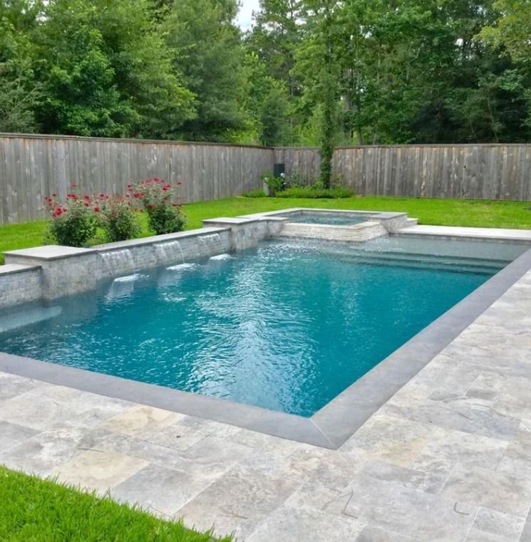 Backyard in-ground pool with turquoise water, stone deck, and wooden privacy fence.
