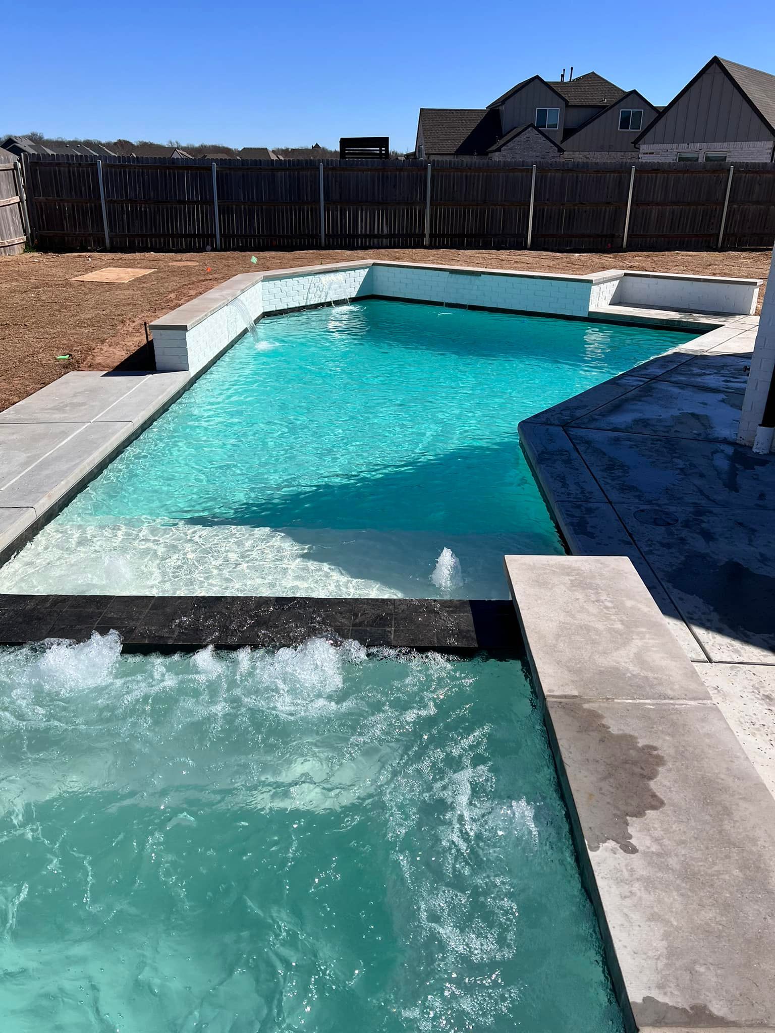 Backyard swimming pool with turquoise water and a small waterfall spillway