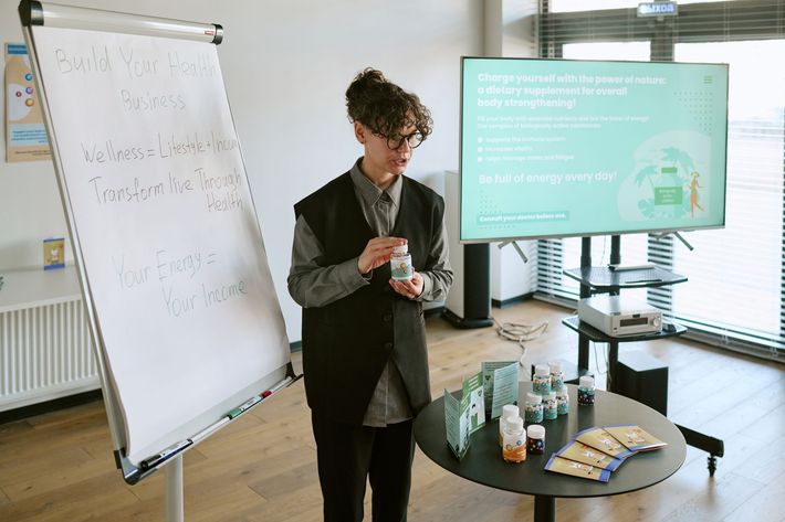 Young woman presenting dietary supplements during business training, explaining wellness sales model and product benefits. 
