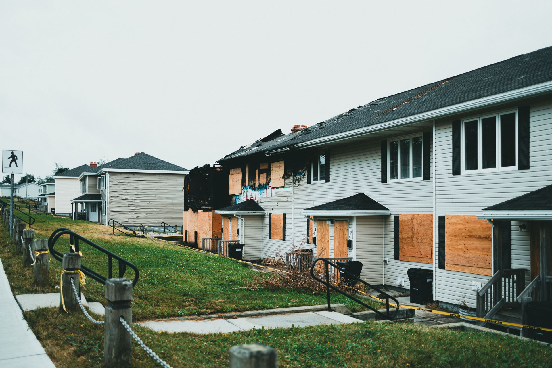 Row of white and brick townhouses along a wet sidewalk on an overcast day