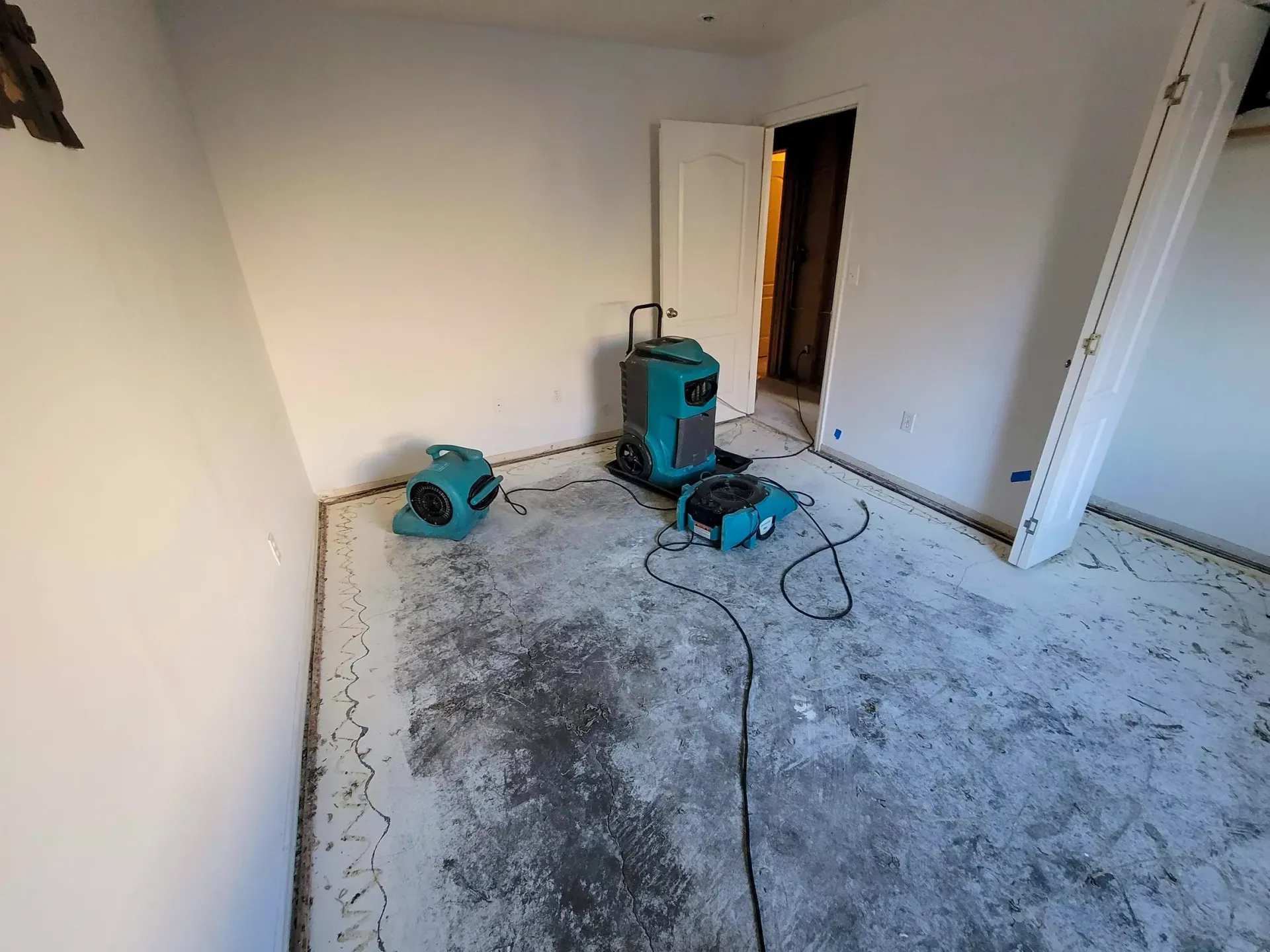 Vacant room under renovation with dusty floor, power tools, and exposed wall opening.