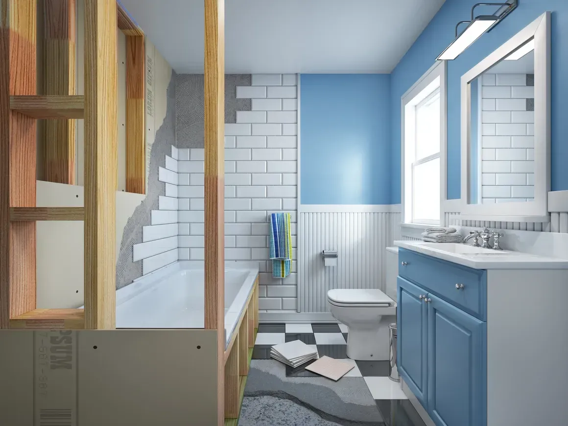 A bathroom under renovation with an exposed wooden frame, half-tiled shower wall, and blue vanity with a white countertop.