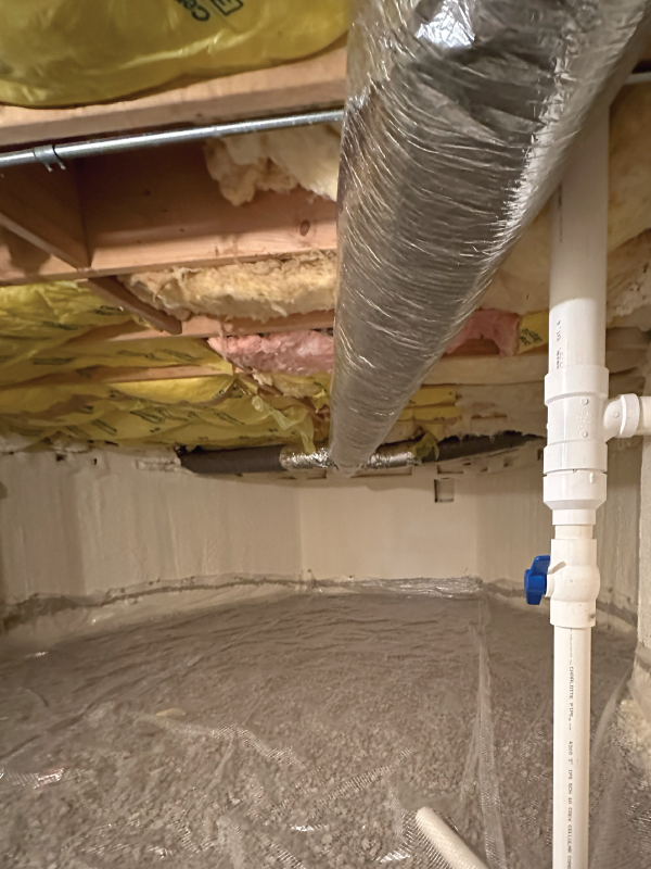 A basement with a lot of pipes and insulation on the ceiling.