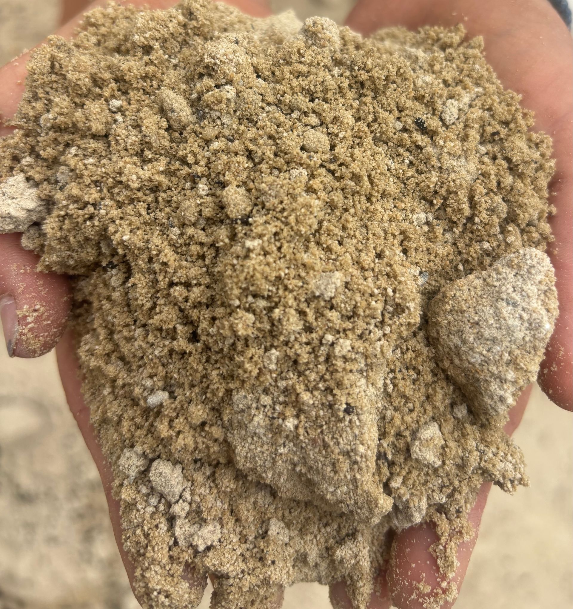 Hands holding a pile of light brown, grainy sand — Schutz Landscape and Garden Supplies in Tomerong, NSW