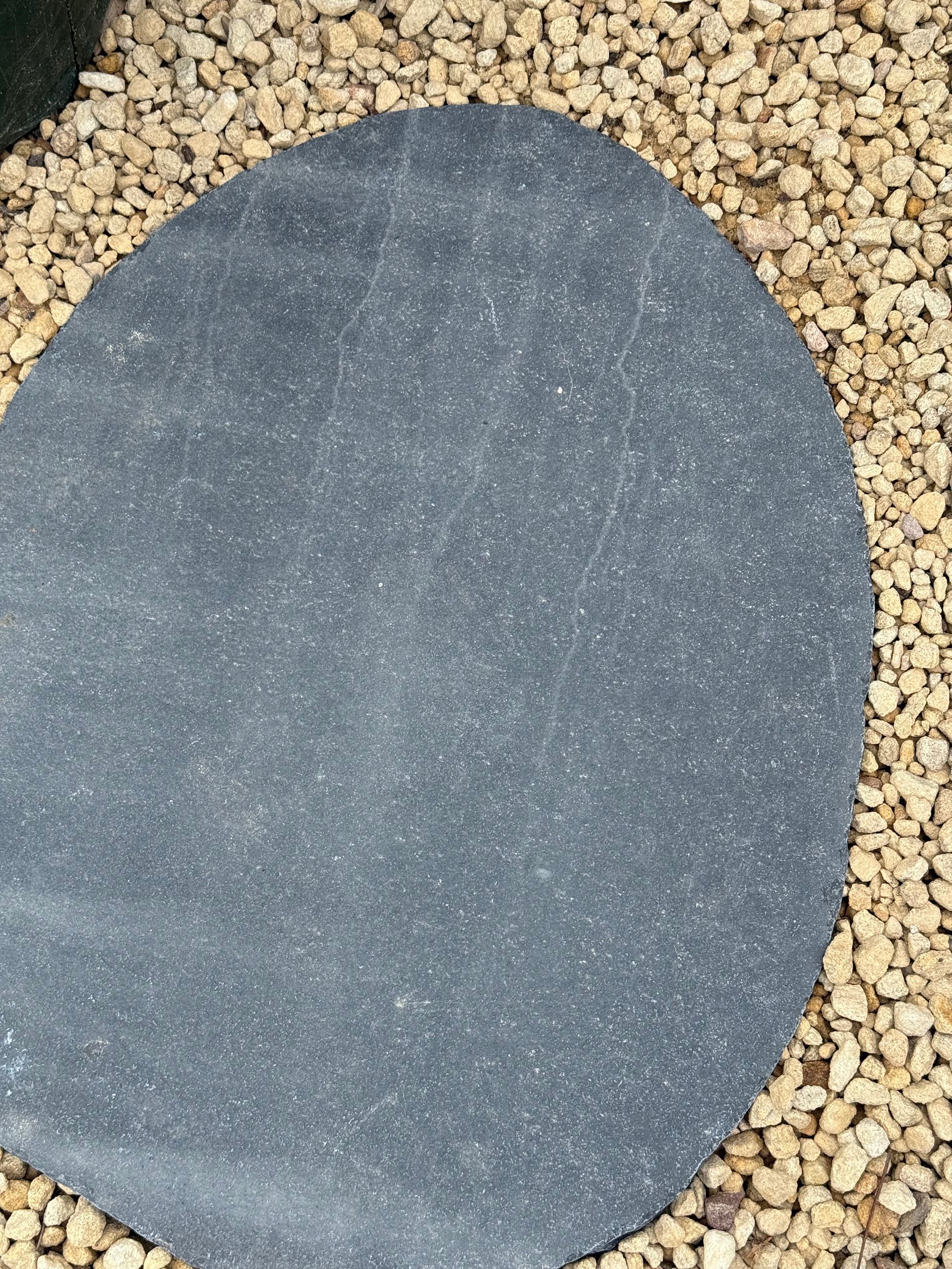 Dark gray, irregularly shaped stepping stone surrounded by small beige gravel  — Schutz Landscape and Garden Supplies in Tomerong, NSW
