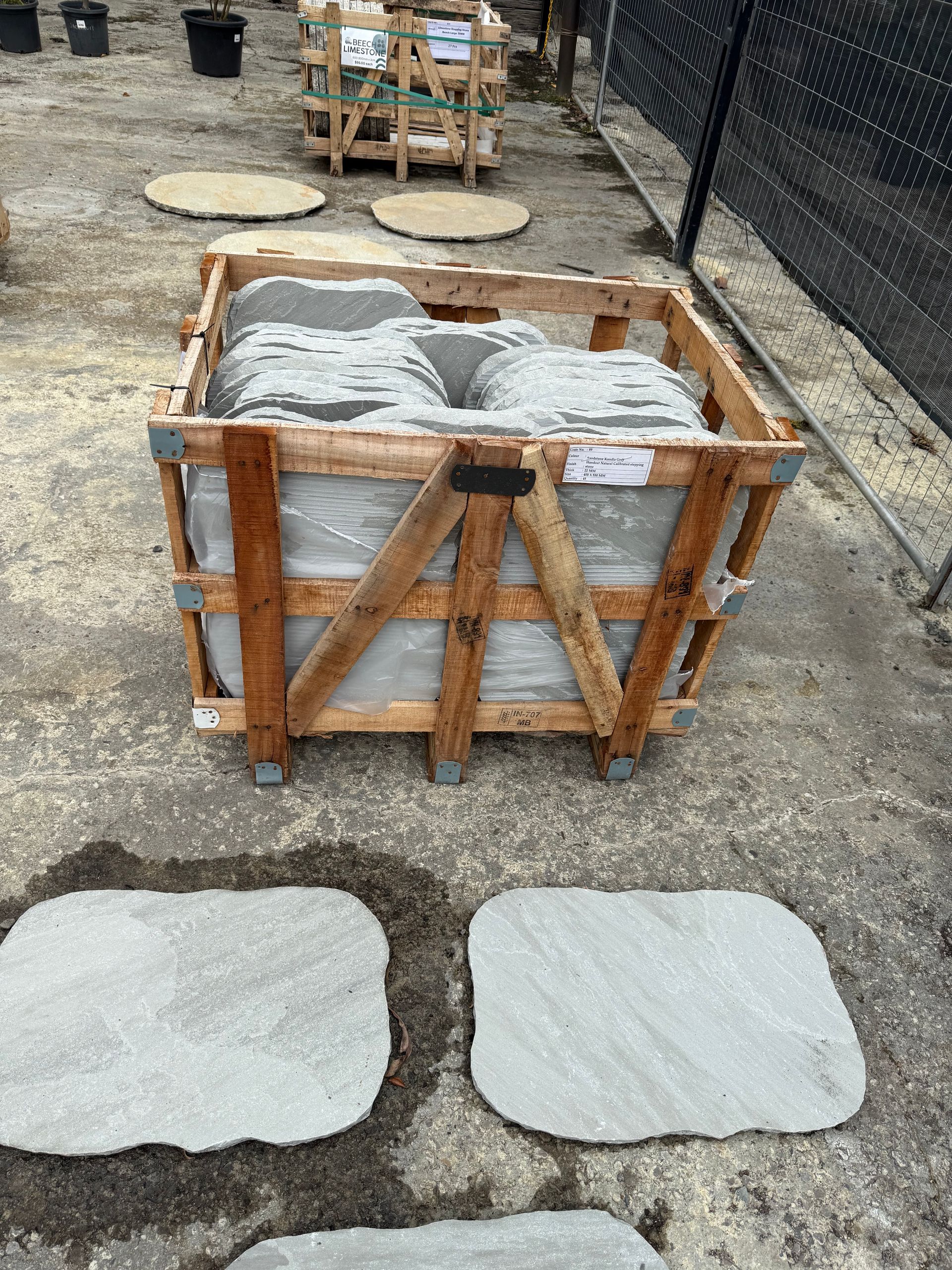 Wooden crate with flagstone pavers, surrounded by other pavers on a concrete surface  — Schutz Landscape and Garden Supplies in Tomerong, NSW