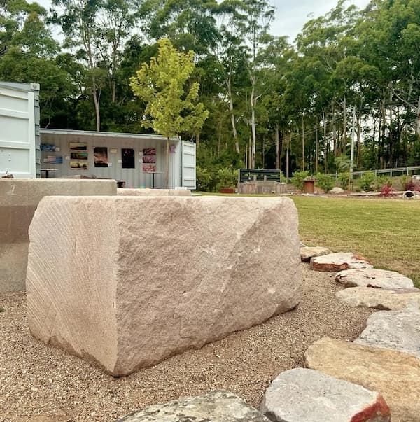 A Large Stone Block Sits In The Middle Of A Grassy Field — Schutz Landscape and Garden Supplies in Tomerong, NSW