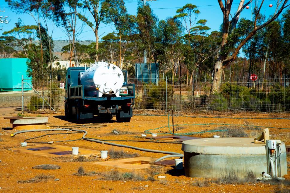 A Tanker Truck Is Parked In A Dirt Field With Trees In The Background — Gympie Septic Pump Outs In Curra, QLD