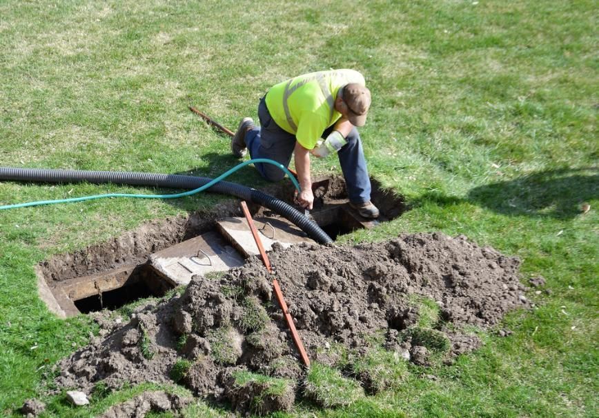 A Man Is Working On A Septic Tank In A Yard — Gympie Septic Pump Outs In Mothar Mountain, QLD
