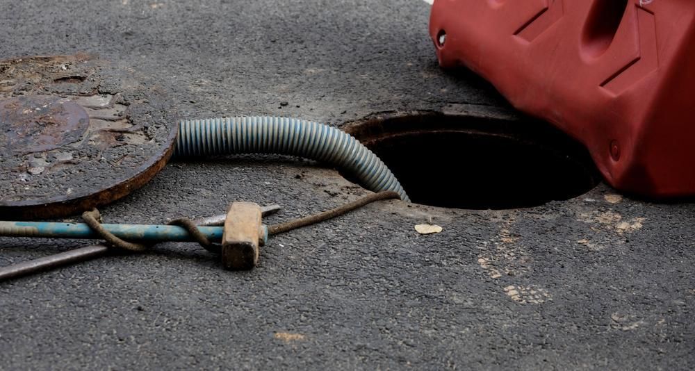 A Manhole Cover With A Hose Coming Out Of It — Gympie Septic Pump Outs In Banks Pocket, QLD