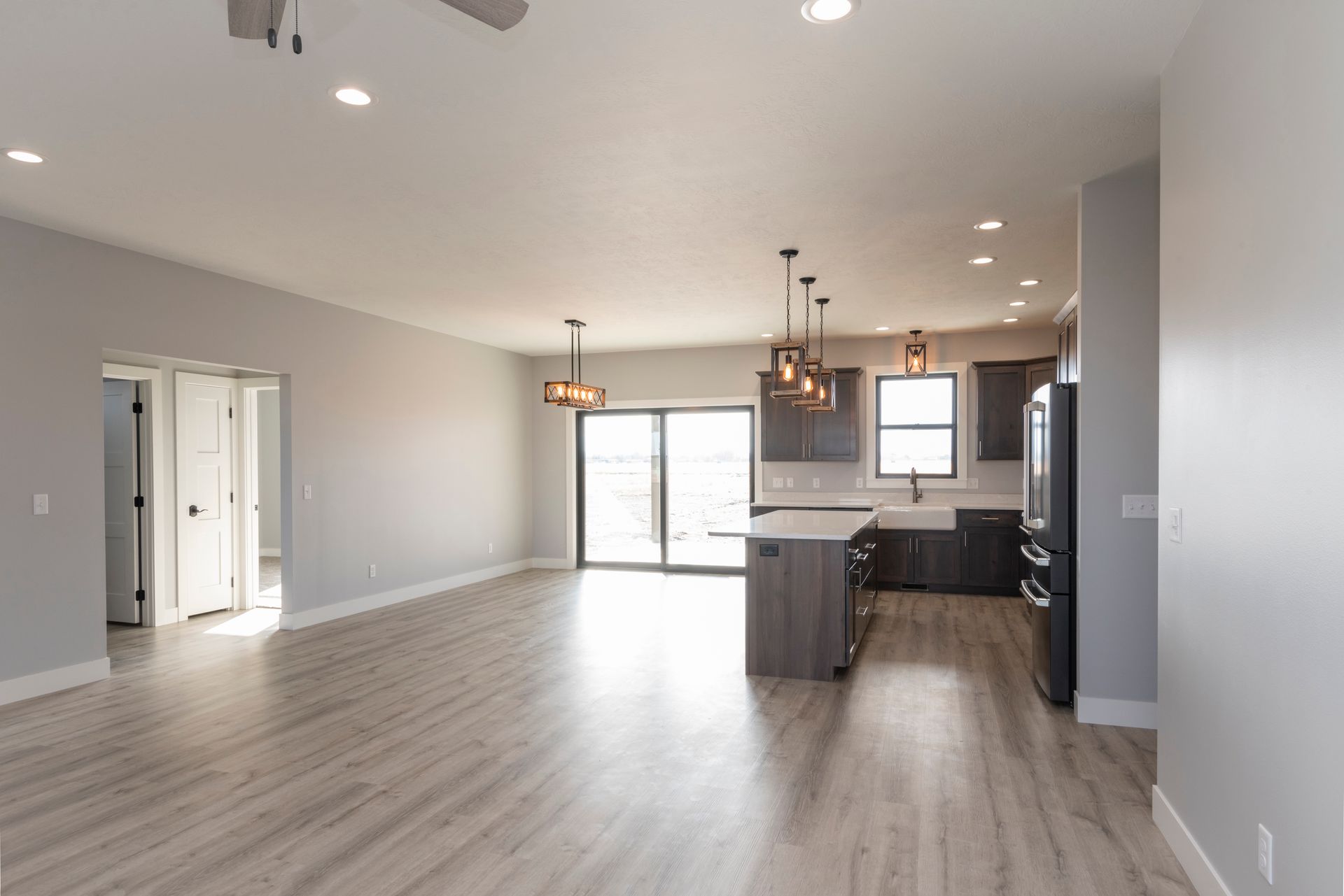 Open-plan living space with gray walls, light wood floors, and a modern kitchen.