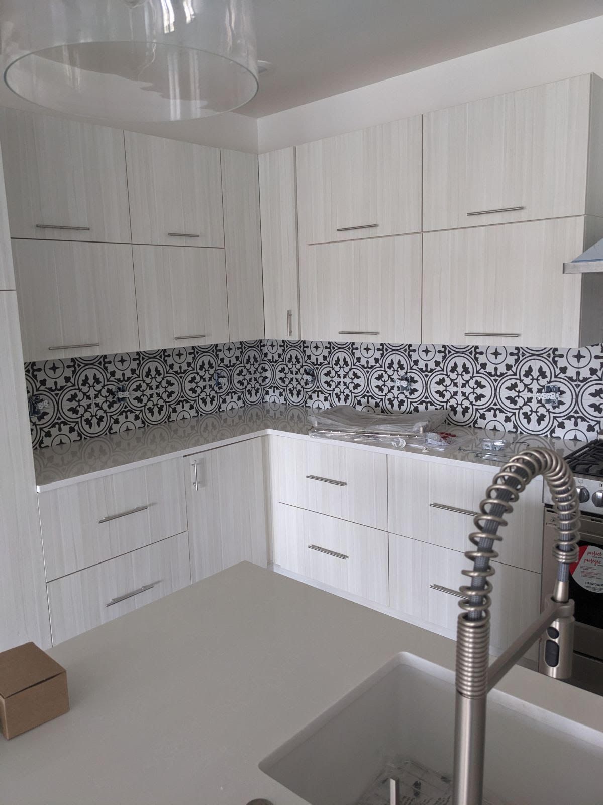 White kitchen cabinets and counter with blue and white tile backsplash.