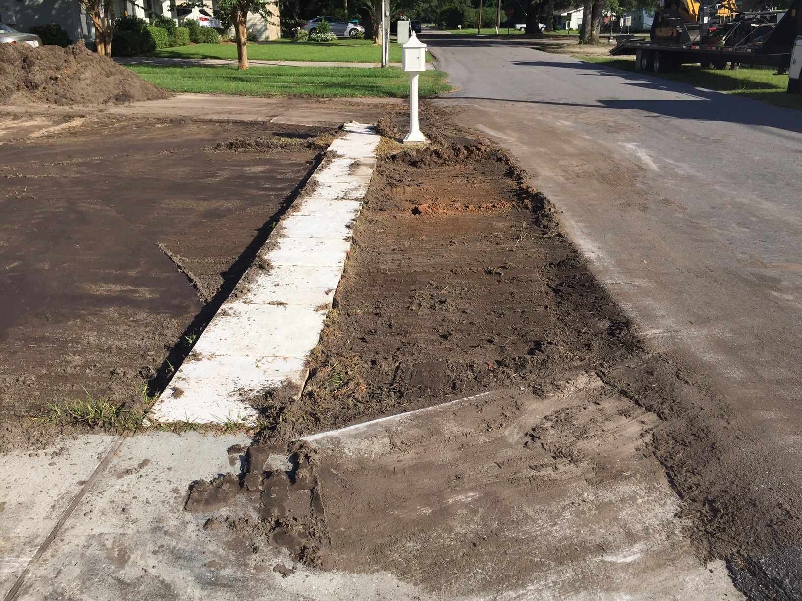 Damaged curb ramp beside a street, with broken concrete and exposed dirt near a sidewalk.