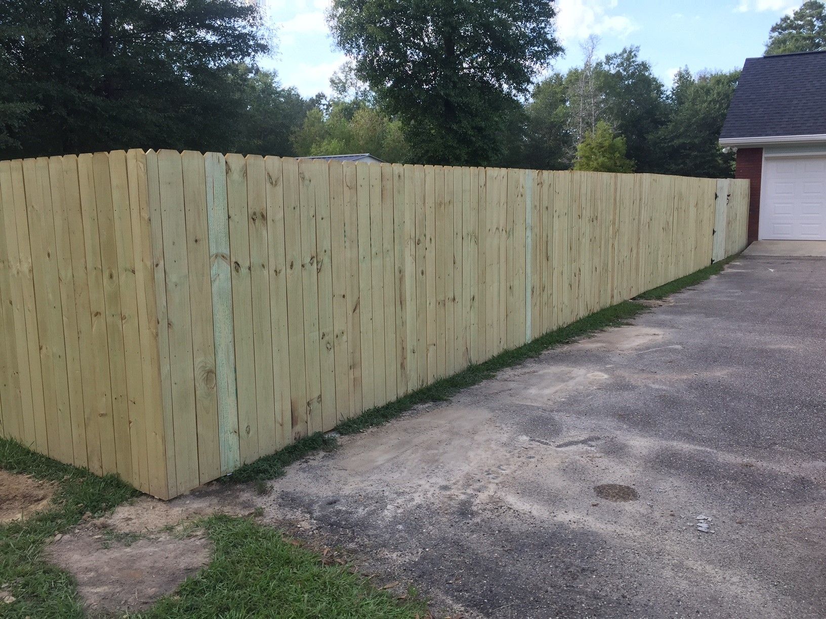 Long wooden privacy fence along a driveway beside a house and garage.