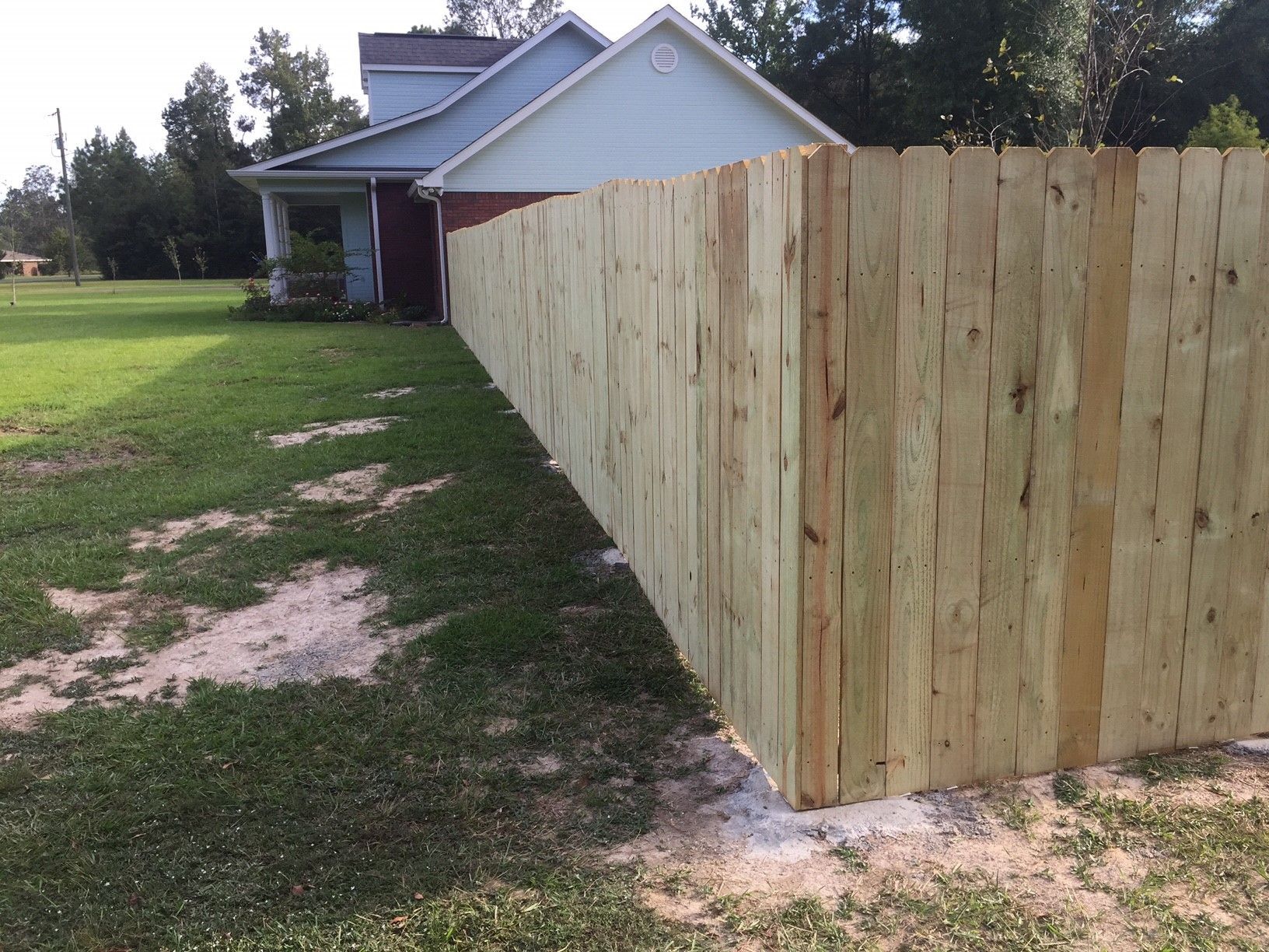 New wooden privacy fence beside a house on a grassy yard