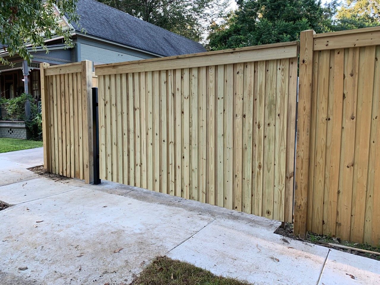 Wooden privacy fence beside a concrete driveway in a residential yard.