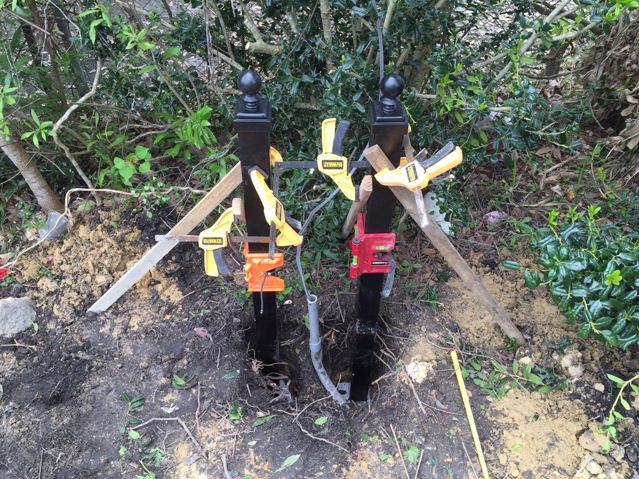 Two utility valves with colored handles beside a small dug-up trench in a wooded area