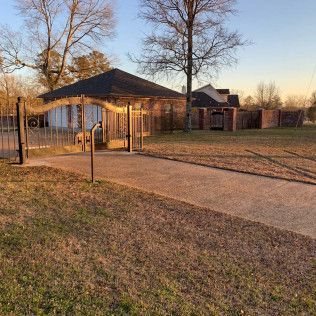Paved walkway leading to a covered playground shelter and brick building at sunset