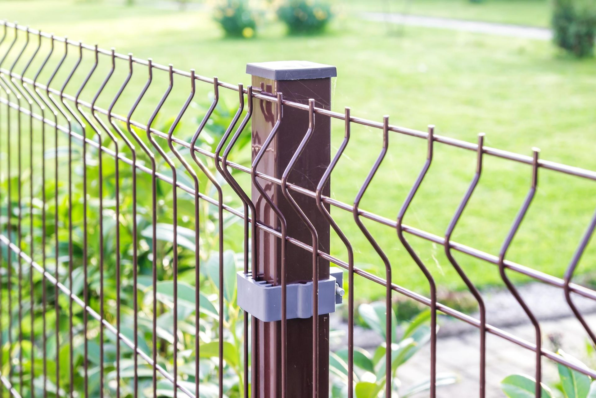 Brown metal fence post with wire mesh fence in a green outdoor yard