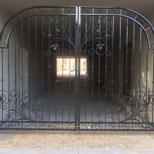 Closed black wrought-iron gate blocking a tunnel-like passage with a bright opening in the distance