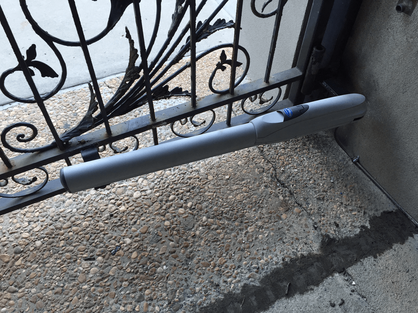 Gray foam pipe insulation wrapped around a black metal gate handle, near a cracked concrete step.