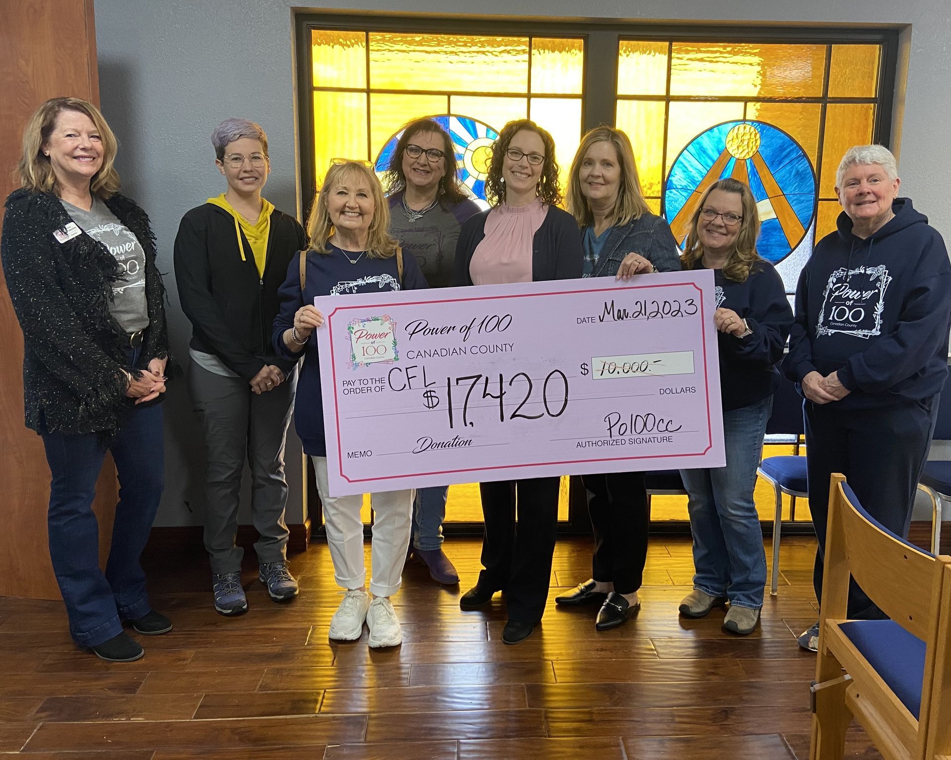 A group of women standing next to each other holding a large check.