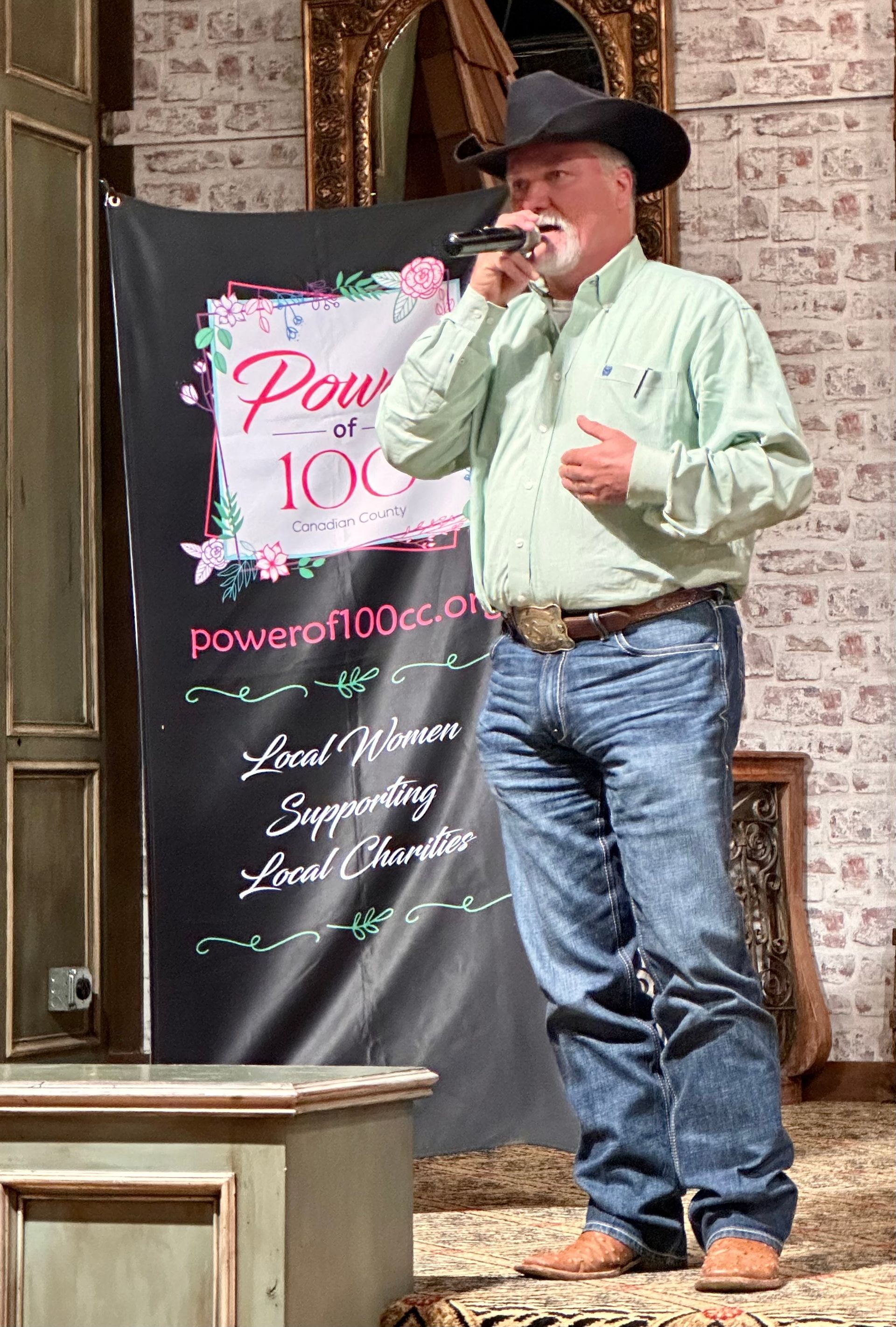 A man in a cowboy hat is standing in front of a microphone.
